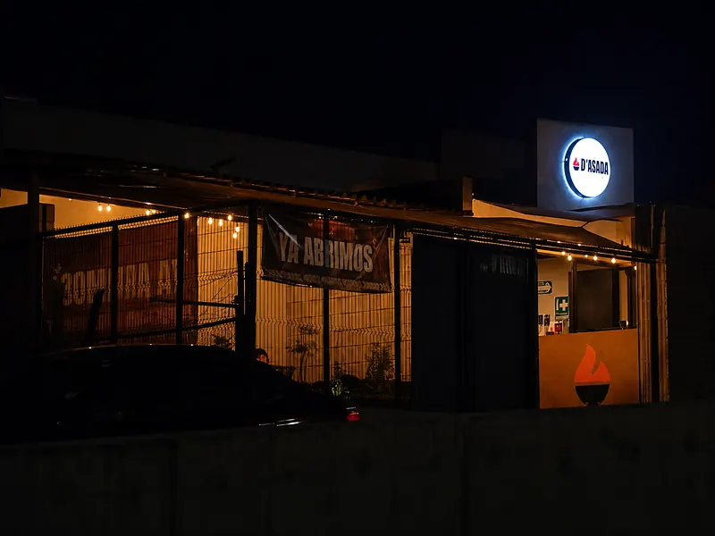 Fachada de noche con el letrero circular iluminado
